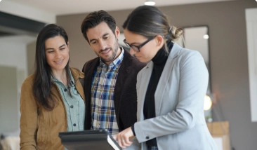  A mortgage broker showing a digital tablet to a couple, likely discussing property details.  