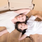 Young couple in white shirts lying on the ground with moving boxes