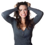Woman with curly hair in distress, pulling her hair.