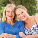 Adult daughter with mother, smiling in the sun.