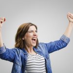 Studio portrait of a successful woman with arms raised