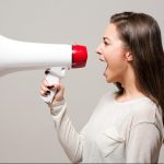 Woman screaming into a megaphone making an announcement