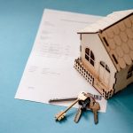 A miniature house and a set of keys on top of a title deed