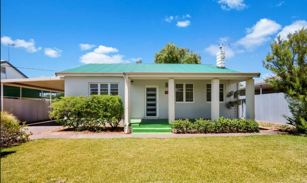 one storey house white house with a green roof and a fornt yard