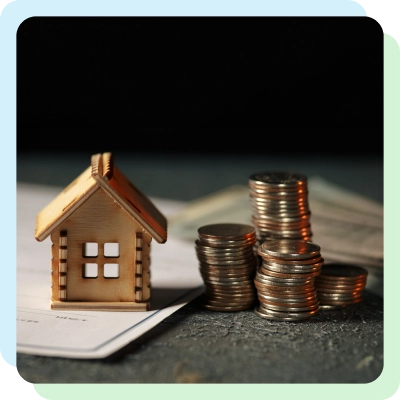 a miniature house along with a stack of coins