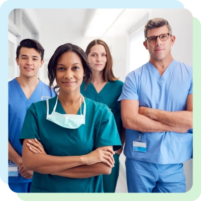 Diverse team of four healthcare professionals in scrubs standing confidently in a hospital corridor.