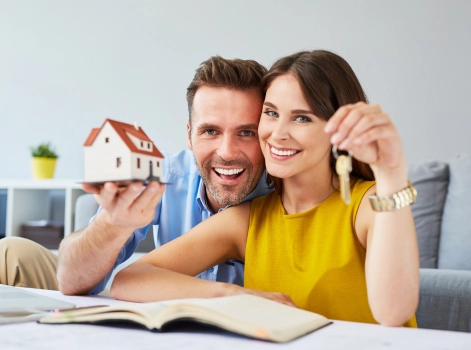 A man and a young girl holding a miniature house and a key