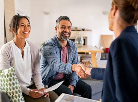 Smiling couple shaking hands with a professional, representing trust and partnership in achieving their homeownership goals through expert mortgage advice.