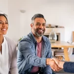 Smiling couple shaking hands with a professional, representing trust and partnership in achieving their homeownership goals through expert mortgage advice.