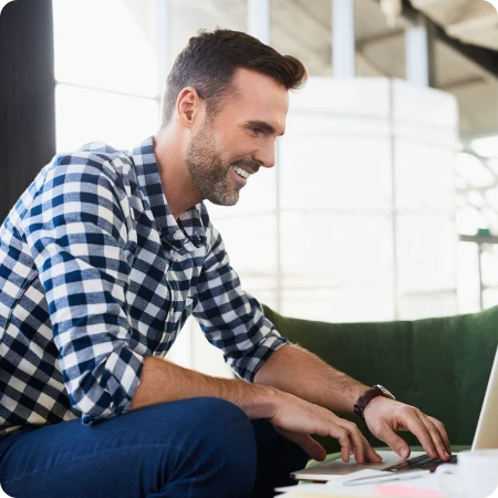 Casual worker with checkered shirt working on a laptop