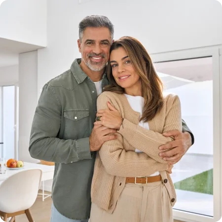 Happy couple embracing in their modern living room, representing homeownership and financial stability.