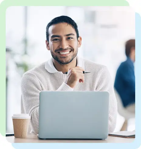 a man smiling with a laptop and coffee in front