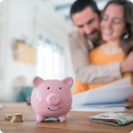 A pink piggy bank sits on a table surrounded by coins and banknotes, symbolizing savings and financial planning.